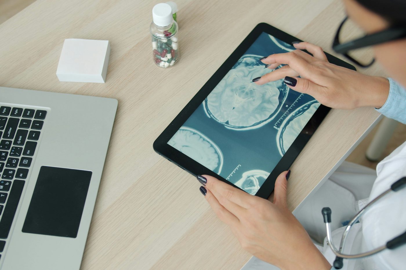 Clinician reviewing medical imaging on a tablet beside a laptop